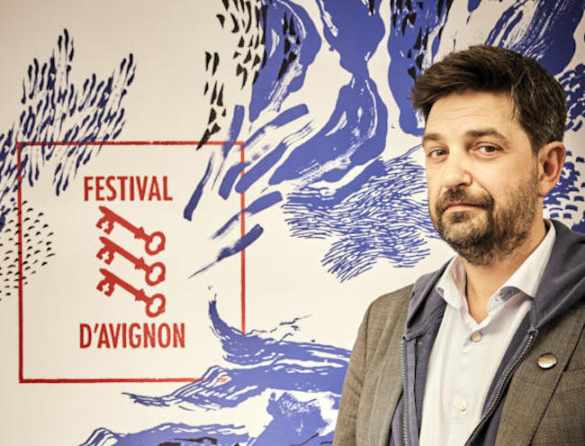 Tiago Rodrigues signe sa première édition en tant que directeur du festival d’Avignon devant l’affiche de la 77e édition. © Raynaud de Lage
