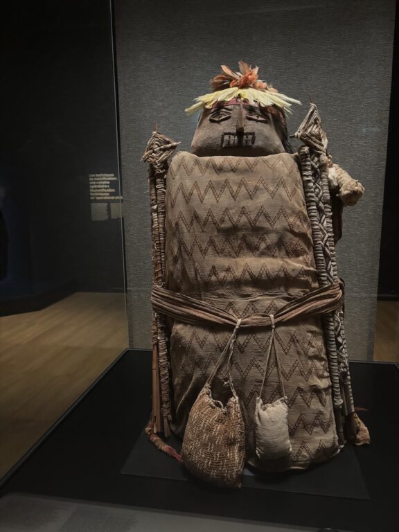 Ce fardo, ou paquet funéraire, contient la dépouille momifiée d’un enfant sud-américain, âgé d’environ 5 ans lors de son décès. Il a été façonné selon un méticuleux processus propre à la culture Chancay, qui s’est développée dans la région centrale de l'actuel Pérou autour du 13e siècle. Le fardo est composé de multiples couches de tissus, entourées de bâtons recouverts de coton qui témoignent du statut social élevé du défunt. Il est surmonté d’une fausse tête couronnée de plumes. ©RIvaud-NAJA