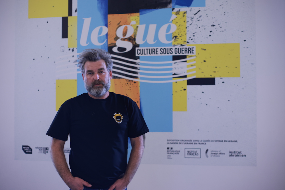 Paiul Gilonne, designer graphiste, devant l'affiche qu'il a composée avec la lettre ukrainienne, le gué, qui explique que « À cause de cette lettre, pas moins de 100 000 intellectuels ont été fusillés, déportés, poussés au suicide dans les années 30-40 ». © Hidalgo-Pietri:NAJ A
